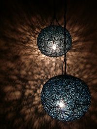 Low angle view of illuminated light bulb hanging from ceiling