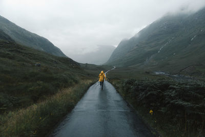 Rear view of woman walking on country road