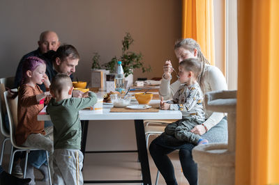 Multi generation family eating meal around kitchen table