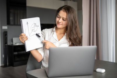 Young woman using digital tablet while sitting on table