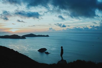 Silhouette people looking at sea against sky during sunset