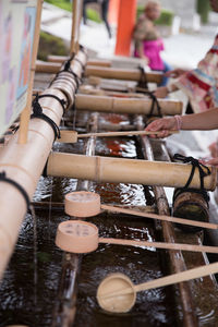 Close-up of cropped hand holding container by drinking water in temple