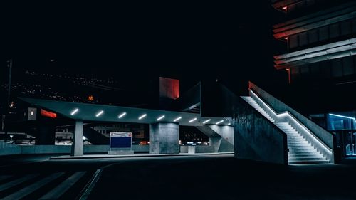 Empty road against illuminated buildings in city at night