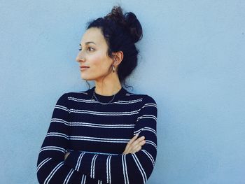Portrait of beautiful young woman standing against wall