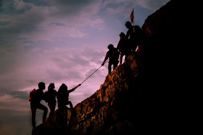 People on rock against sky