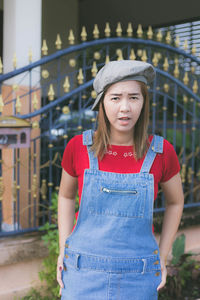 Portrait of smiling woman standing against gate 