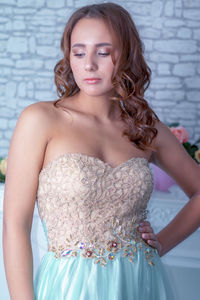 Portrait of beautiful young woman standing against wall