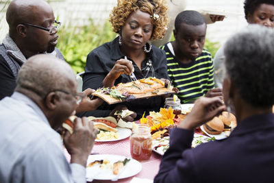 Family and friends eating food while sitting at table