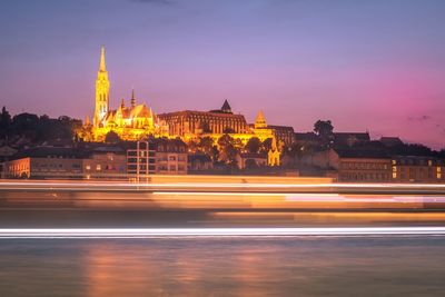 Light trails on street against illuminated buildings 