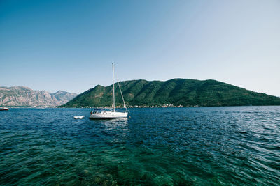 Sailboat sailing on sea against clear blue sky