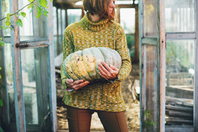 A young woman holding in her hands aripe pumpkin crop yields. thanksgiving and halloween preparation