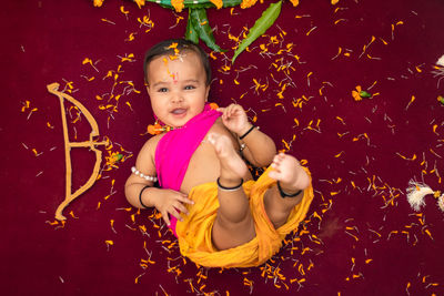 Cute indian boy dresses as lord rama with bow and flowers from top angle