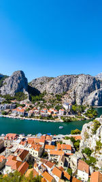 Buildings by sea against clear blue sky