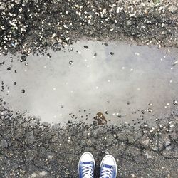 Low section of man standing on road by puddle