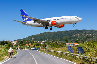 Airplane flying over road against sky