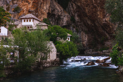 River amidst trees and buildings against mountain