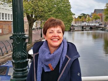 Portrait of smiling mature woman against water in city