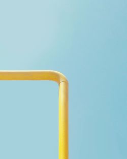 Low angle view of yellow pipe against clear blue sky