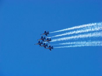 Low angle view of airshow against clear blue sky