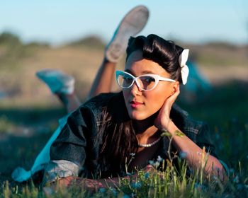 Portrait of young woman wearing eyeglasses while lying on grass