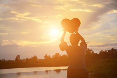 Silhouette woman standing against sky during sunset