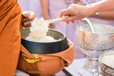 Old woman hand put rice in alms bowl of buddhist monk on morning