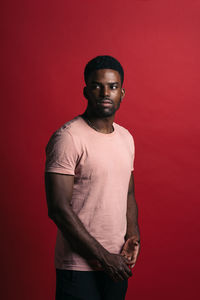 Portrait of young man standing against red background