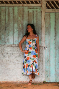 Portrait of young woman standing against wall