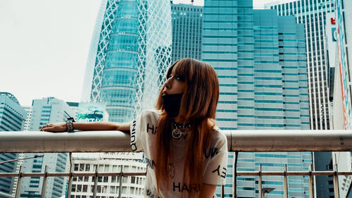 Woman standing by modern buildings in city