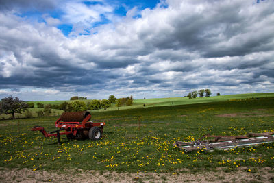 People sitting on bench on field against sky