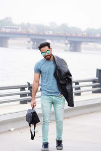 Full length of man standing on railing against water