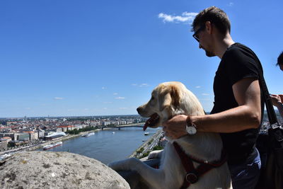 Side view of man with dog against sky