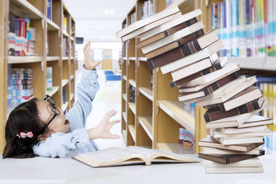 Books falling on girl in library