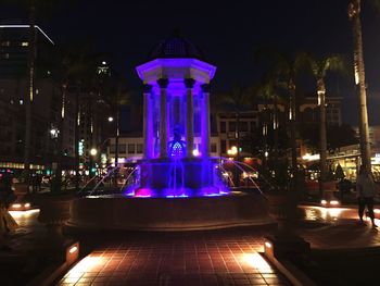 Illuminated fountain against building at night