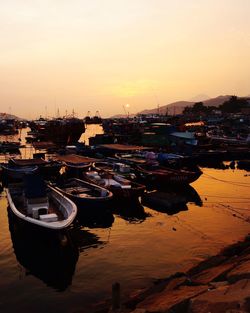 Boats moored on riverbank during sunset