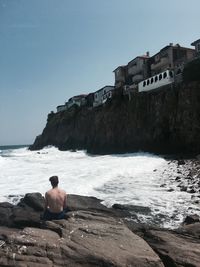 Man sitting on rock against sea