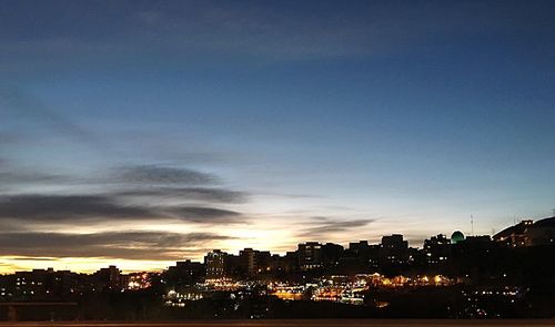 Illuminated cityscape against sky at night