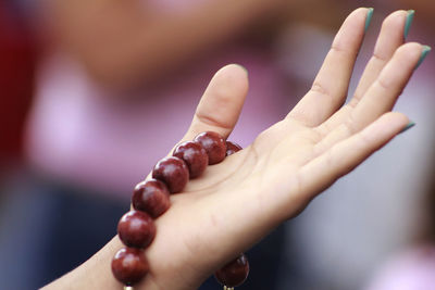 Close-up of woman hand holding bead necklace