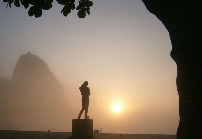 Silhouette woman standing by sea against clear sky during sunset