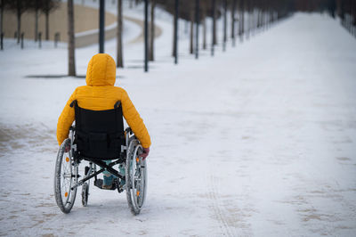 Rear view of man riding bicycle on snow