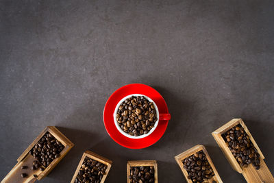 High angle view of roasted coffee beans in spoons and crockeries on table