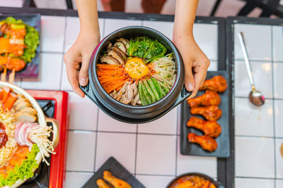 High angle view of woman holding food on table