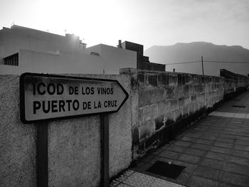 Information sign on wall against sky