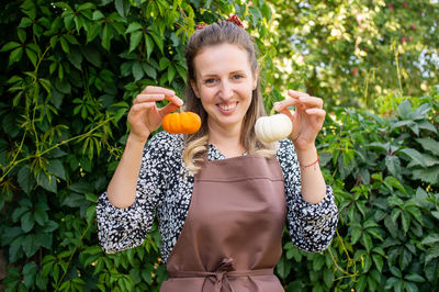 Cute farmer girl holding two small pumpkins in her hands