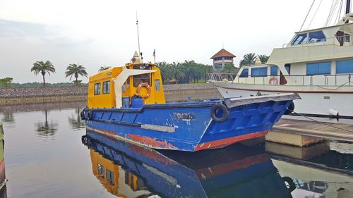 Fishing boat moored on lake by buildings against sky