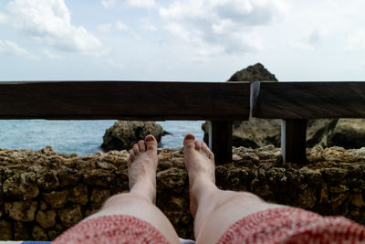 Low section of person on beach against sky