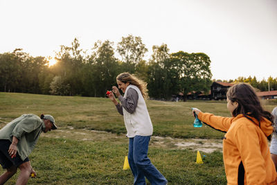 Girl spraying water on female counselor while having fun in playground at summer camp