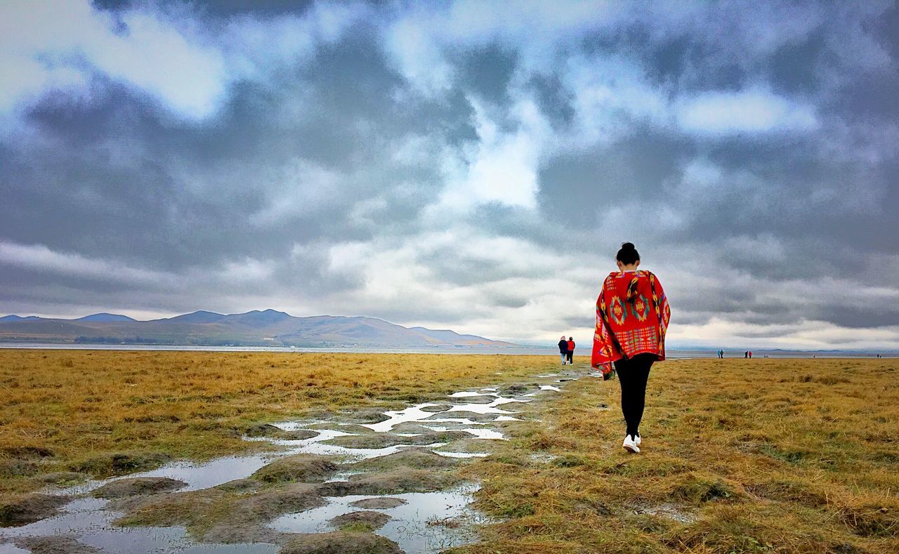 full length, rear view, casual clothing, landscape, tranquil scene, sky, tranquility, cloud - sky, scenics, vacations, nature, beauty in nature, mountain, day, getting away from it all, non-urban scene, tourism, outdoors, solitude