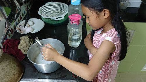 Side view of cute girl preparing food in kitchen