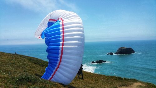 Scenic view of paraglidier on cliff and sea against sky